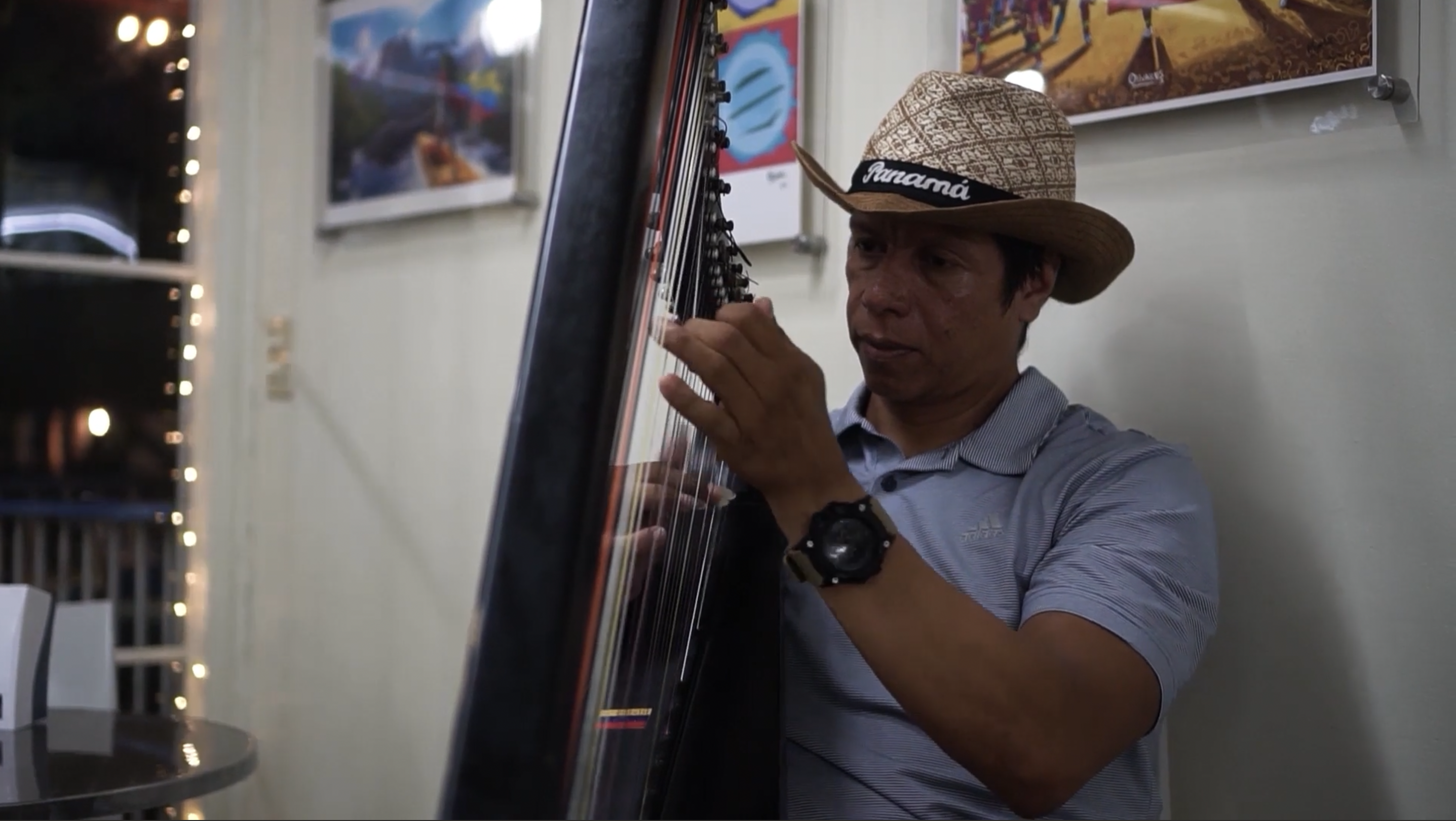 A musician playing the harp while wearing a hat that says 'Panam&aacute;'